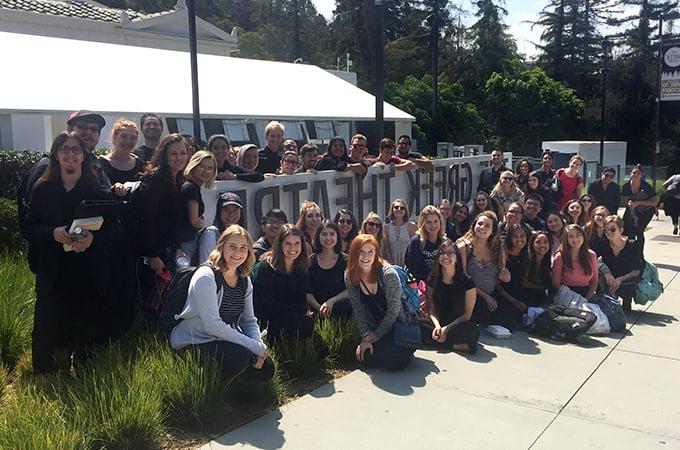 Members of Chapel Singers and Bel Canto choirs stand in front of the Greek Theater sign in L.A.